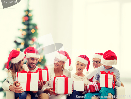 Image of happy family in santa helper hats with gift boxes