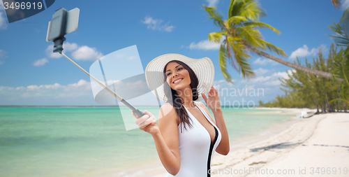 Image of happy woman taking selfie with smartphone on beach