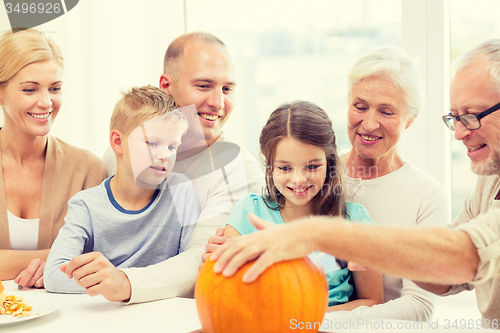 Image of happy family sitting with pumpkins at home