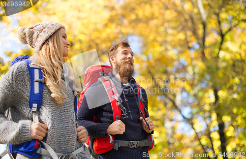 Image of smiling couple with backpacks hiking over autumn