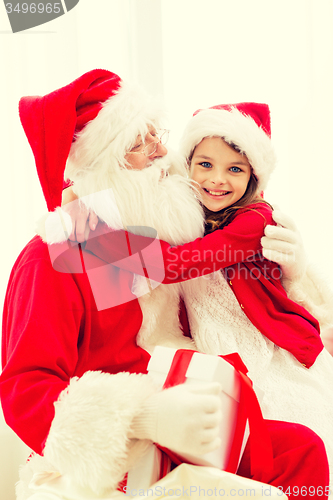 Image of smiling girl with santa claus and gift at home