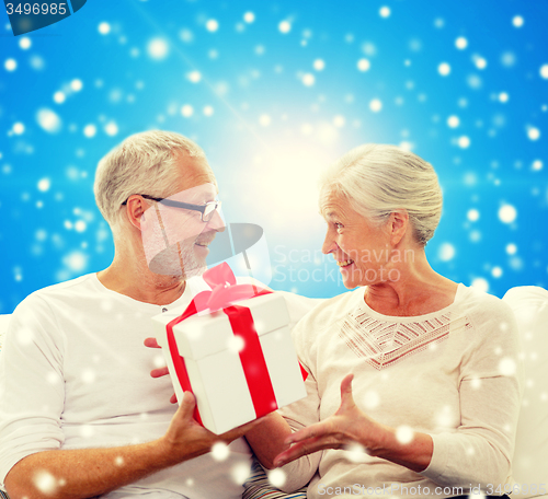 Image of happy senior couple with gift box at home