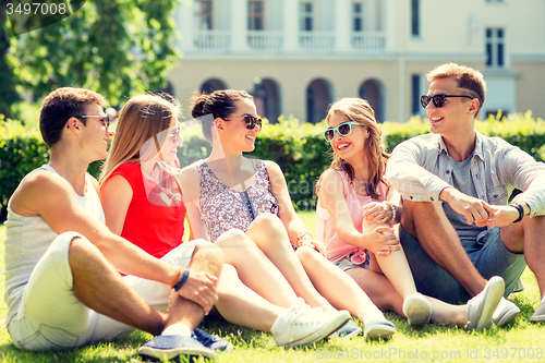 Image of group of smiling friends outdoors sitting on grass