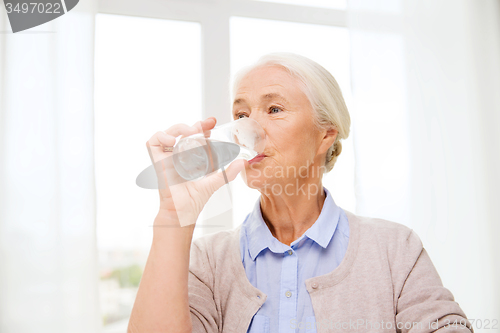 Image of happy senior woman with glass of water at home