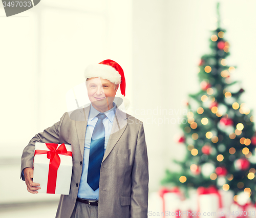 Image of smiling man in suit and santa helper hat with gift