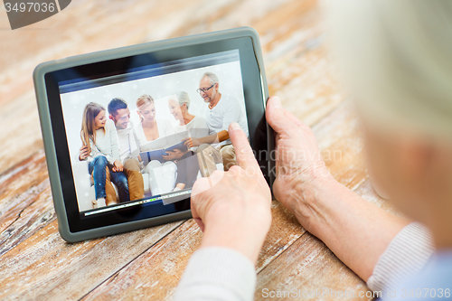 Image of senior woman with family photo on tablet pc screen