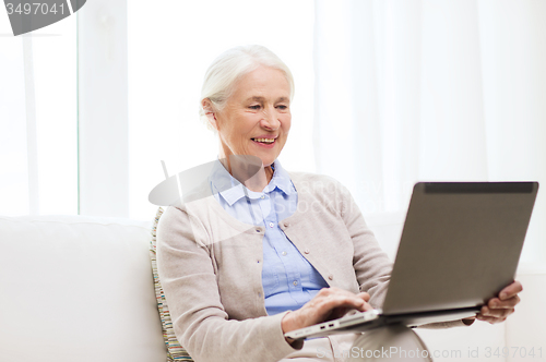 Image of happy senior woman with laptop at home