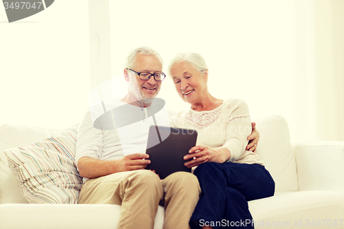 Image of happy senior couple with tablet pc at home