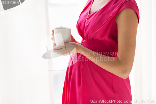 Image of pregnant woman with cup drinking tea at home