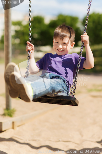 Image of happy little boy swinging on swing at playground