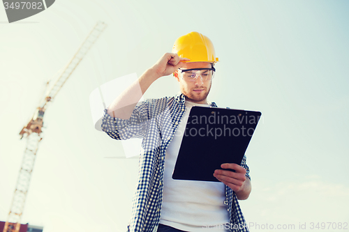 Image of builder in hardhat with clipboard outdoors