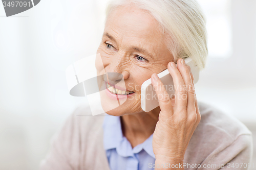 Image of senior woman with smartphone calling at home