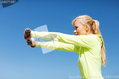 Image of sporty woman with light dumbbells outdoors