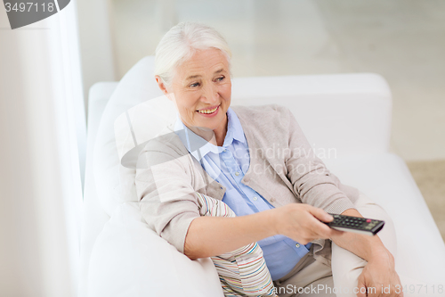 Image of happy senior woman watching tv at home