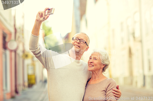 Image of senior couple photographing on city street