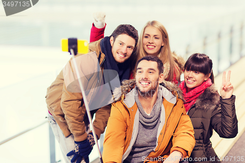 Image of happy friends with smartphone on skating rink