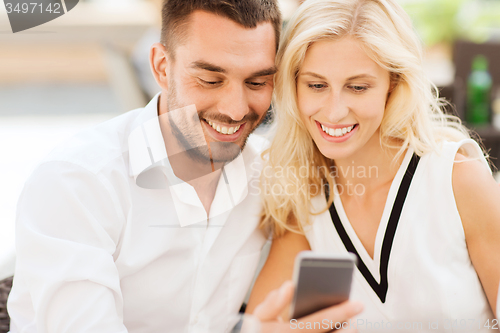 Image of happy couple with smartphone at city street cafe