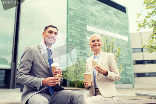 Image of smiling businessmen with paper cups outdoors