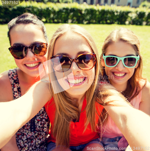 Image of group of smiling teen girls taking selfie in park