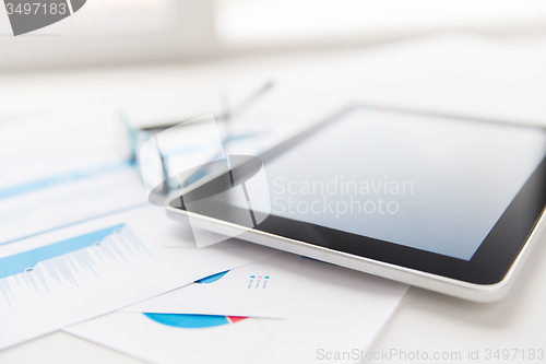 Image of close up of tablet pc, glasses and files in office