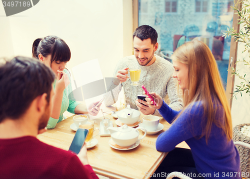 Image of group of friends with smartphones meeting at cafe