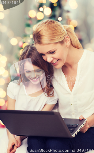 Image of smiling mother and little girl with laptop