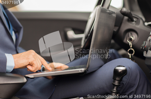 Image of close up of young man with laptop driving car
