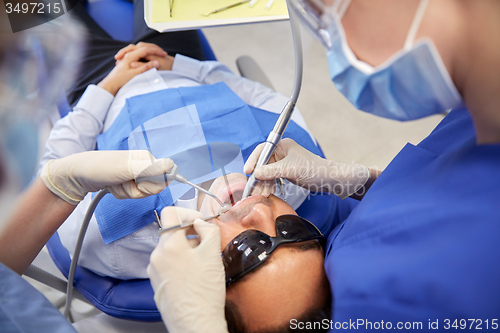 Image of female dentist treating male patient teeth