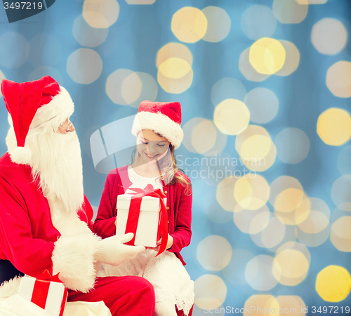 Image of smiling little girl with santa claus and gifts