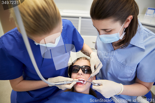 Image of female dentists treating patient girl teeth