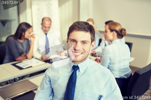 Image of group of smiling businesspeople meeting in office