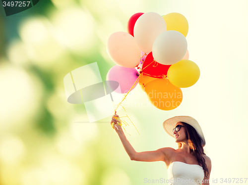 Image of smiling young woman in sunglasses with balloons