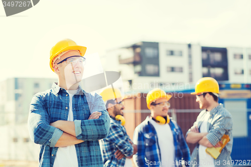 Image of group of smiling builders in hardhats outdoors