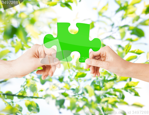 Image of hands with green puzzle over natural background