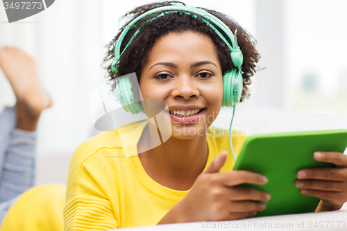 Image of happy african woman with tablet pc and headphones