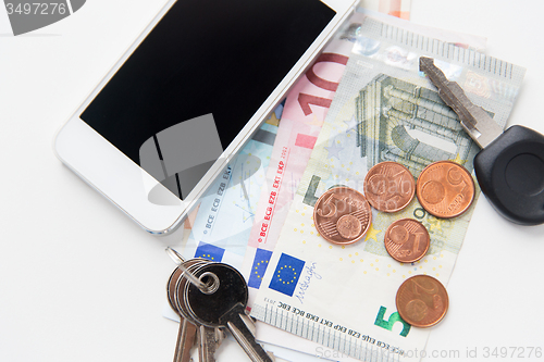 Image of close up of smartphone, money and keys on table