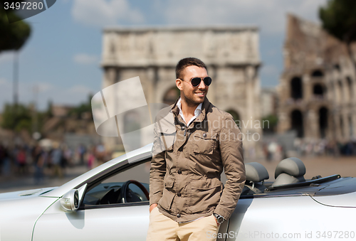 Image of happy man driving cabriolet car over city of rome