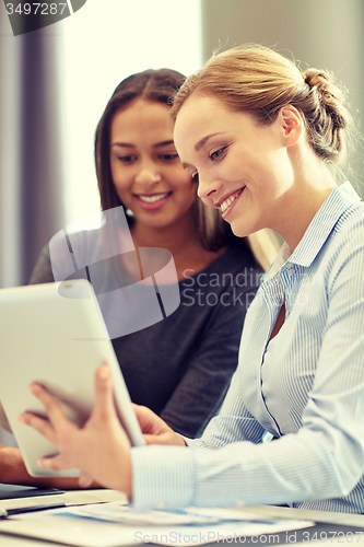 Image of smiling businesswomen with tablet pc in office