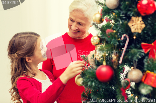 Image of smiling family decorating christmas tree at home