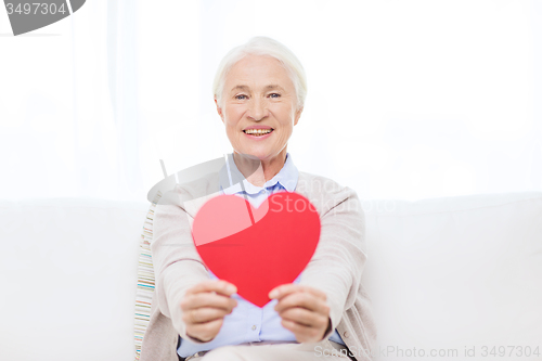 Image of happy smiling senior woman with red heart at home