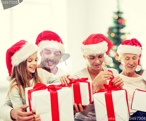 Image of happy family in santa helper hats with gift boxes