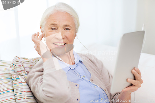 Image of senior woman with tablet pc and earphones at home