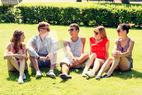 Image of group of smiling friends outdoors sitting on grass