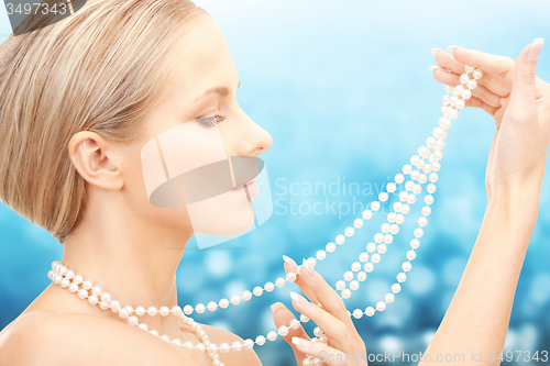 Image of beautiful woman with sea pearl necklace over blue