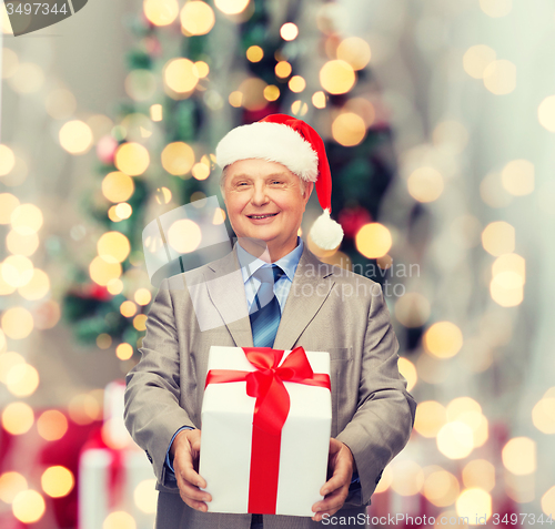 Image of smiling man in suit and santa helper hat with gift