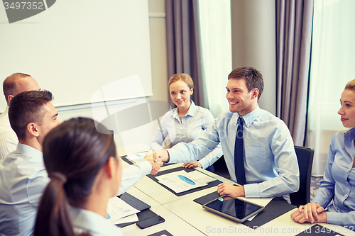Image of group of smiling business people meeting in office