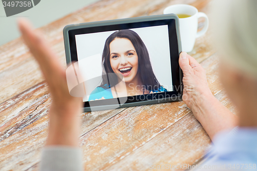 Image of senior woman with photo on tablet pc at home