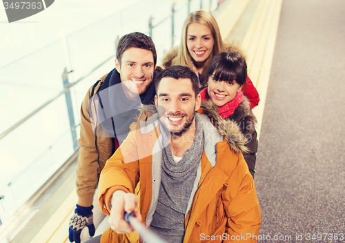 Image of happy friends taking selfie on skating rink