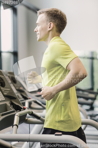 Image of smiling man exercising on treadmill in gym