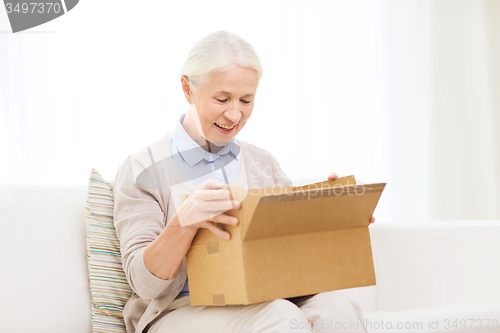 Image of happy senior woman with parcel box at home